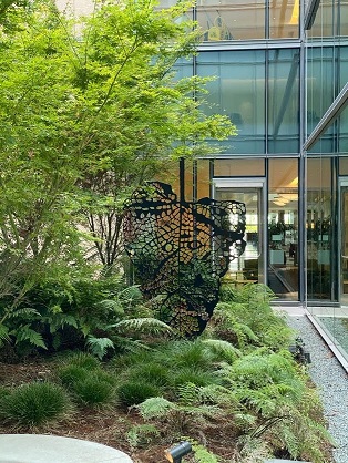 sculpture, modern, reseumbling a leaf, in a courtyard with plants 